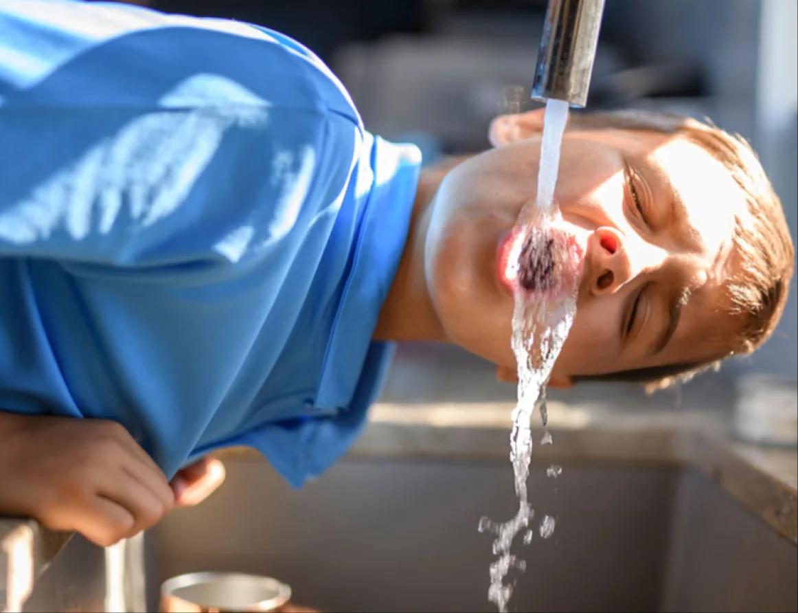 Child drinking water from a tap