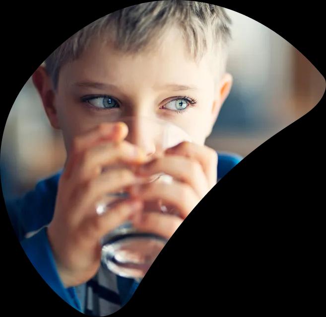 A boy drinking a glass of safe water