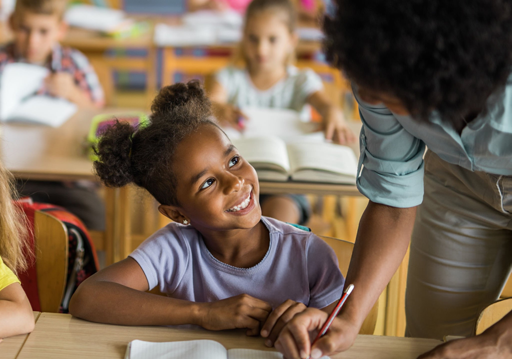 Teacher and student smiling interactively in a classroom setting