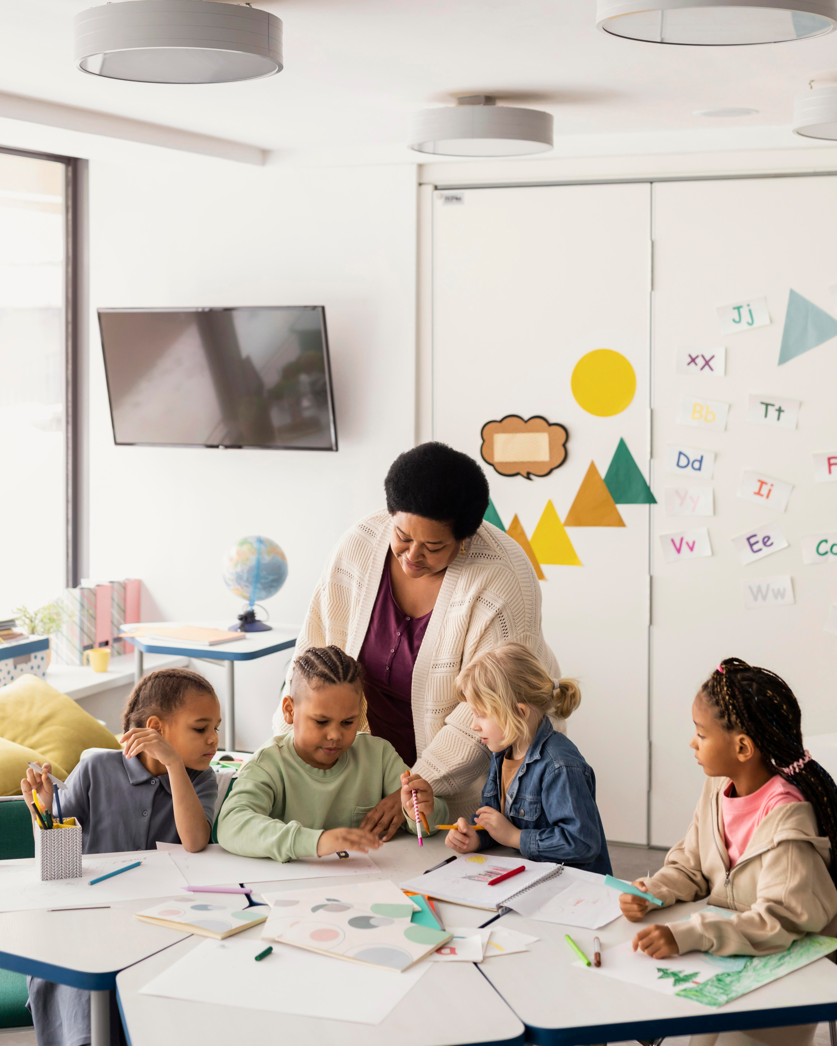 Teacher and young students looking at papers on a desk